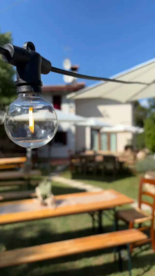 Tavolata in giardino con lampadina decorativa e ombrelloni