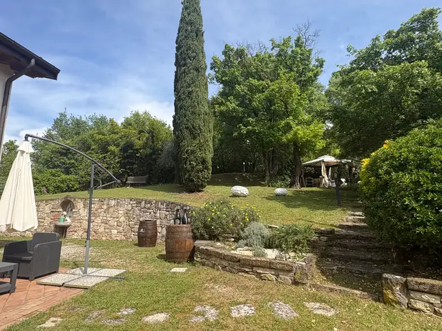 Angolo del giardino con cipresso e muretto in pietra